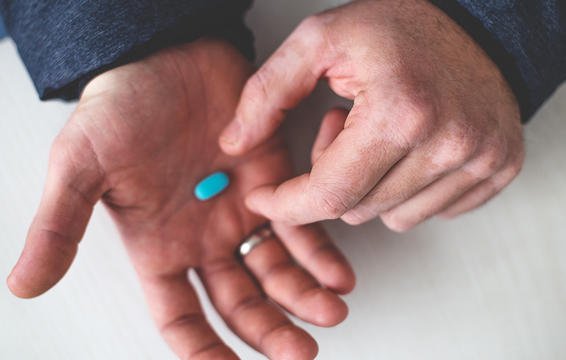 close up on man dropping a blue pill into his other hand